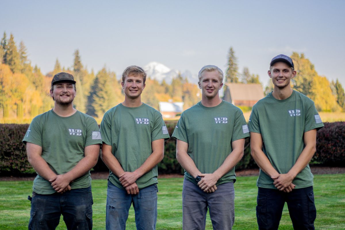 The Washburn Brothers Lawncare crew standing on a freshly mowed lawn in Whatcom County, WA with a snow-capped mountain behind them